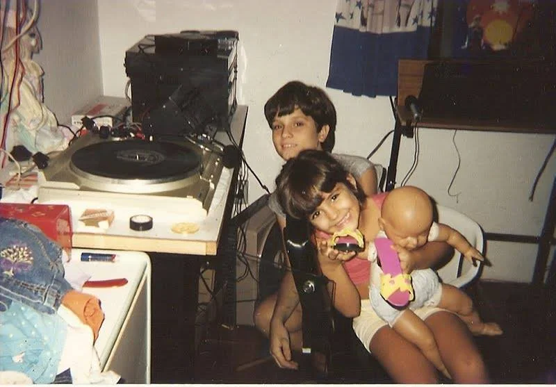 Ariel ainda menino diante de uma pick-up, discos e equipamentos de som em casa